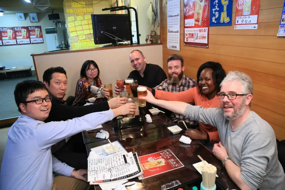 Group of international customers raising drinks together at an izakaya restaurant table in Hokkaido, Japan