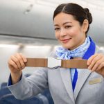 Flight attendant doing safety demonstration - holding belt